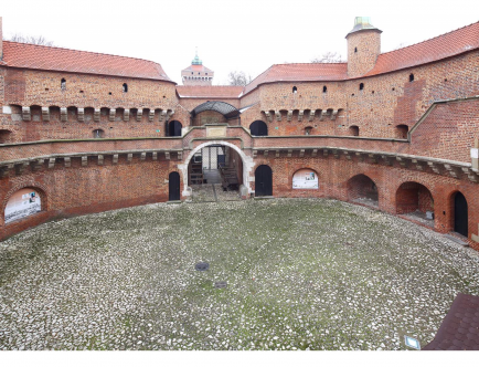 Kolorowa fotografia budynku Barbakanu oraz jego dziedzińca.