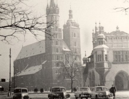 Zdjęcie Krakowa w sephi. Widok z rogu ulicy Sławkowkiej na kościół Mariacki. Na płycie rynku znajdują się cztery samochody i ludzie. Zima.