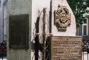 Fotografia kolorowa. Na obelisku centralnie u góry krzyż harcerski. Poniżej tablica frontowa. Pod tablicą wyżłobiony w kamieniu symbol Polski Walczącej. Z boku dwie tablice z nazwiskami poległych harcerzy